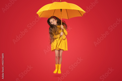 Happy emotional girl laughing with umbrella on colored red background. Autumn, spring season.