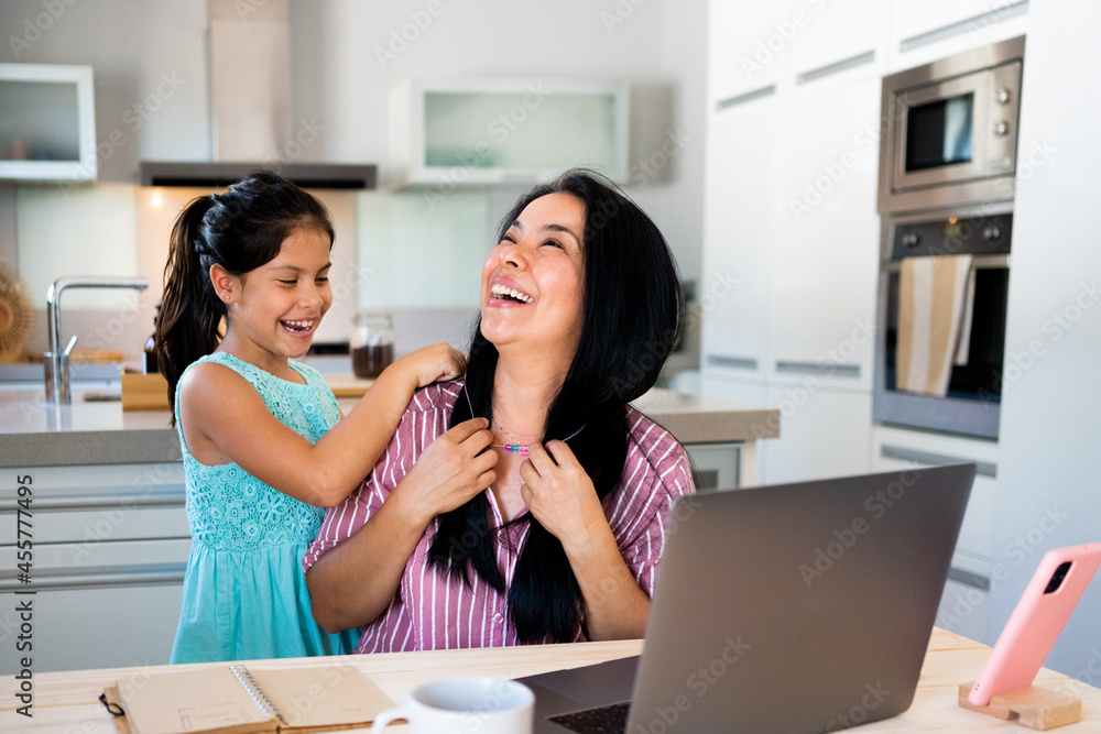 Joyful mother working at home with her daughter Joyful mother working at home with her daughter
