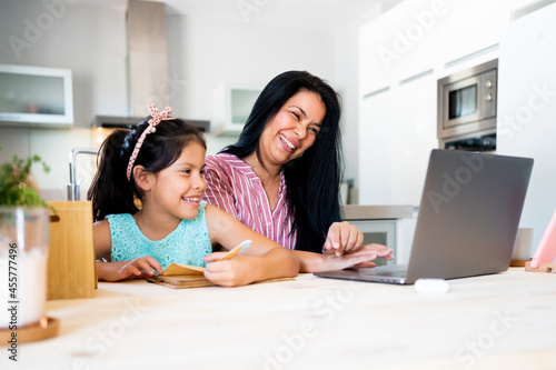 Joyful mother working at home with her daughter photo