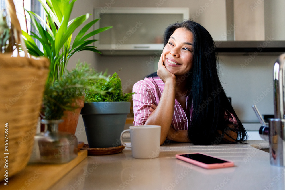 Young woman smiling looking to the window at kitchen Young woman smiling looking to the window at kitchen