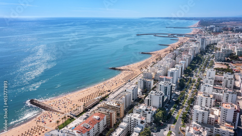 Beautiful aerial cityscapes of the tourist Portuguese city of Quarteira. On the seashore during the beach season with tourists who are sunbathing.