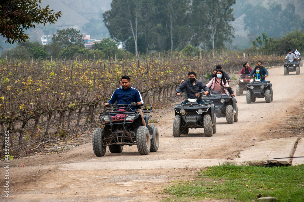 Women and men on ATVs are enjoying a ride in a field Women and men on ATVs are enjoying a ride in a field