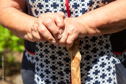 Senior woman hands with wooden walking stick, close up view