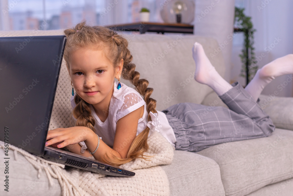 A school student, a little girl working on a laptop, enjoys using technology in teaching. Use of modern devices for educational purposes A school student, a little girl working on a laptop, enjoys using technology in teaching. Use of modern devices for educational purposes