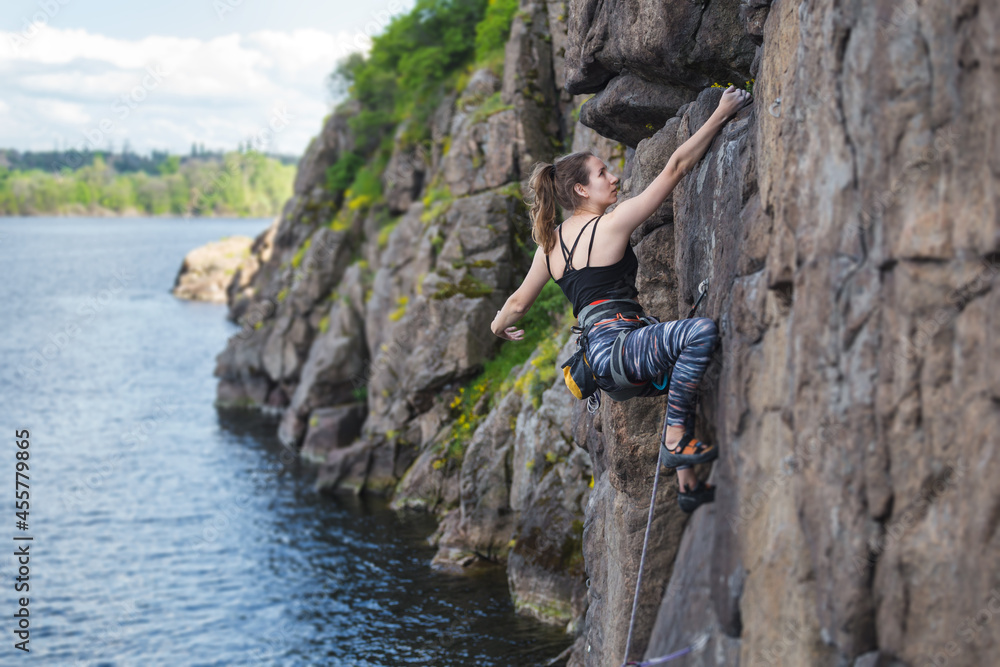 A girl climbs a rock above the water