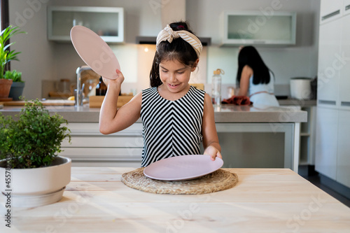 Young girl preparing the dining table at kitchen photo