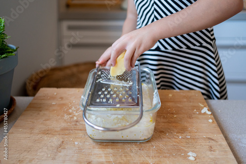 Child grating cheese using a manual grater at kitchen photo