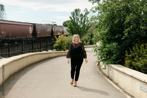 Blond Woman Walking on City Path by Train Tracks