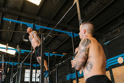 Male trainer looking at athlete on bar photo