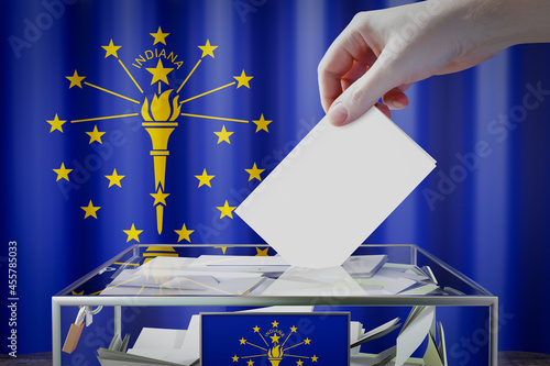 Indiana flag, hand dropping ballot card into a box - voting, election concept - 3D illustration