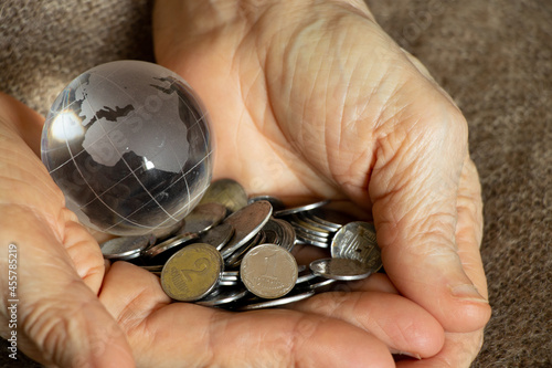 Ukrainian pennies and a glass globe of the planet lies in the hands of an old woman, finance photo