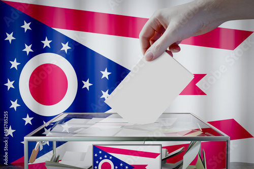 Ohio flag, hand dropping ballot card into a box - voting, election concept - 3D illustration photo