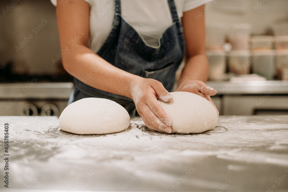 Woman shapes sourdough loaves on a counter top. Woman shapes sourdough loaves on a counter top.