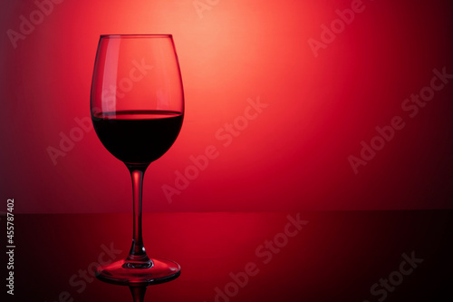 Glass of red wine on a red background on the table