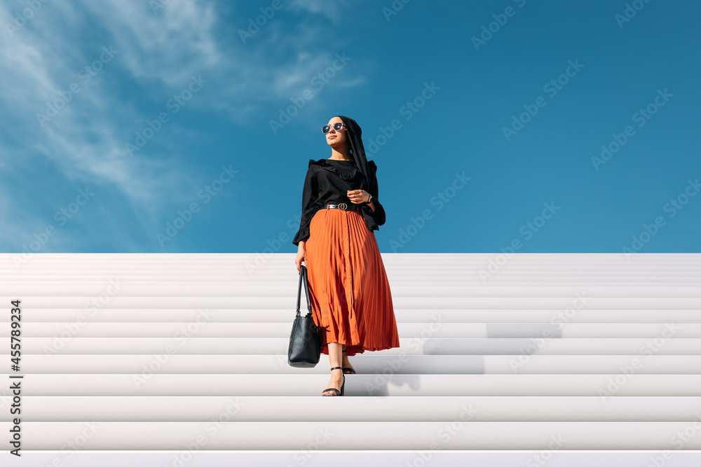 © VICTOR TORRES/Stocksy - Fashionable Muslim woman in stylish clothes and sunglasses © VICTOR TORRES/Stocksy - Fashionable Muslim woman in stylish clothes and sunglasses