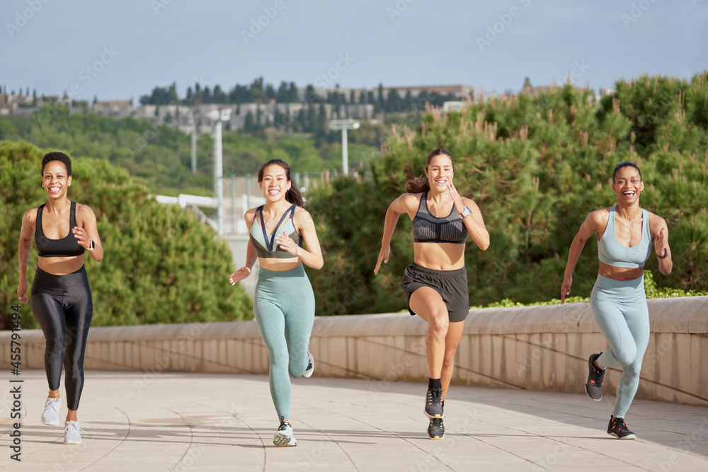Delighted sportswomen running during training in city Delighted sportswomen running during training in city