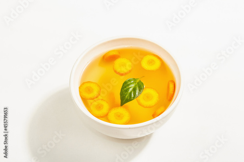 Transparent chicken broth with vegetables in ceramic bowls