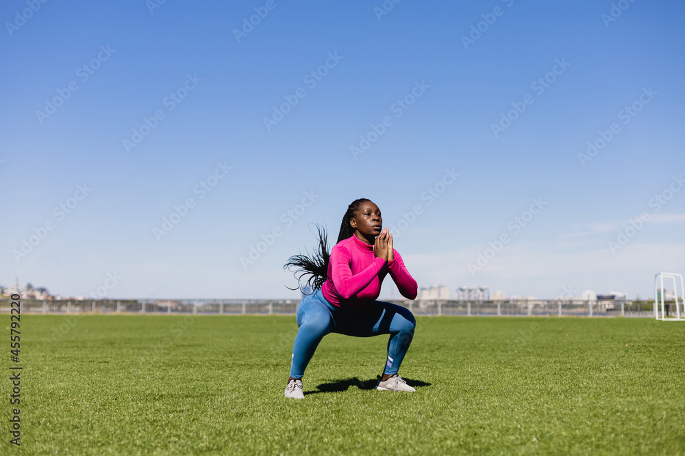 Active black sportswoman doing squats during training Active black sportswoman doing squats during training