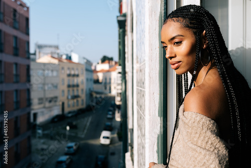 Beautiful black woman with braided long hair standing in a balcony