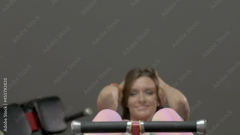 Young woman doing crunches on the bench abs exercising in the gym. Caucasian fitness girl during workout. Sport and health care concept Young woman doing crunches on the bench abs exercising in the gym. Caucasian fitness girl during workout. Sport and health care concept