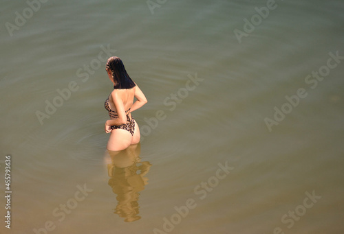 Jovem rapariga bonita dentro de água de uma albufeira com um fato de banho a imitar pele de leopardo, praia fluvial photo