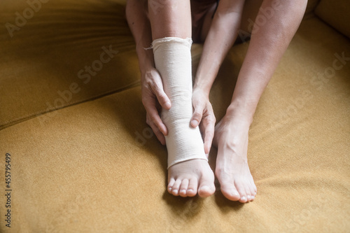 Woman touching her bandaged ankle with both hands