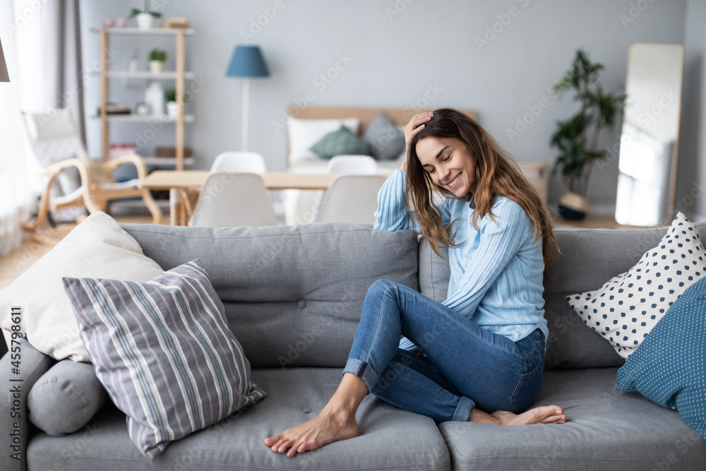 Cute smiling woman on the couch in a cozy interior Cute smiling woman on the couch in a cozy interior