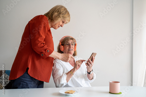 Senior friends at home looking at phone and talking photo