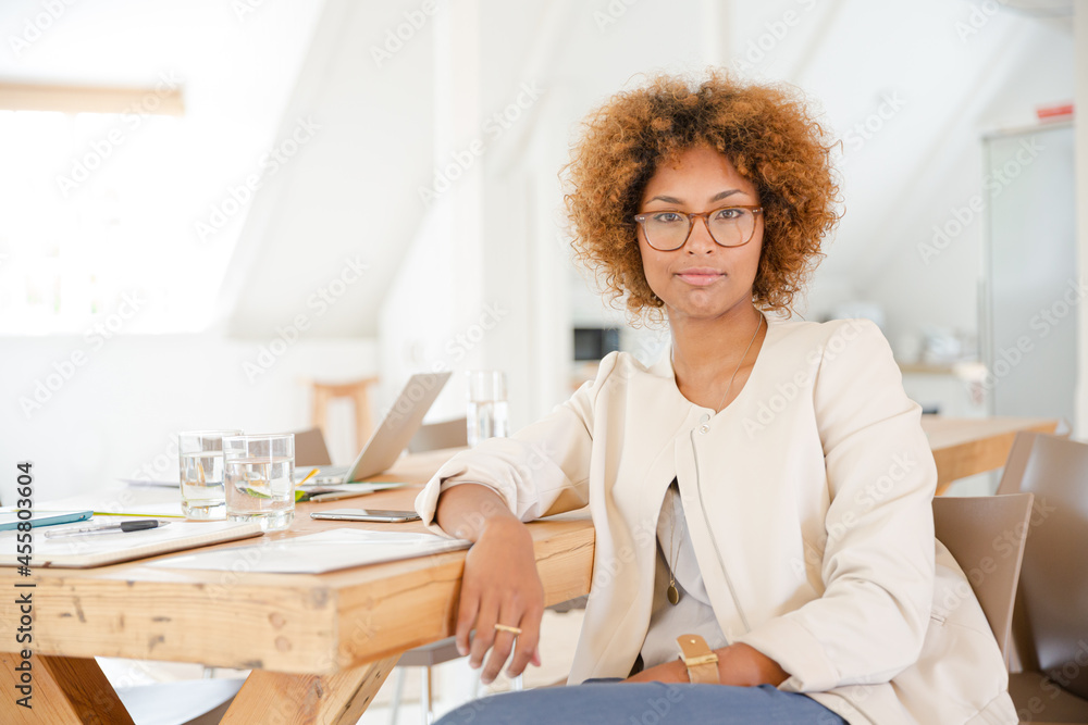 Portrait of woman sitting at desk in office and smiling Portrait of woman sitting at desk in office and smiling