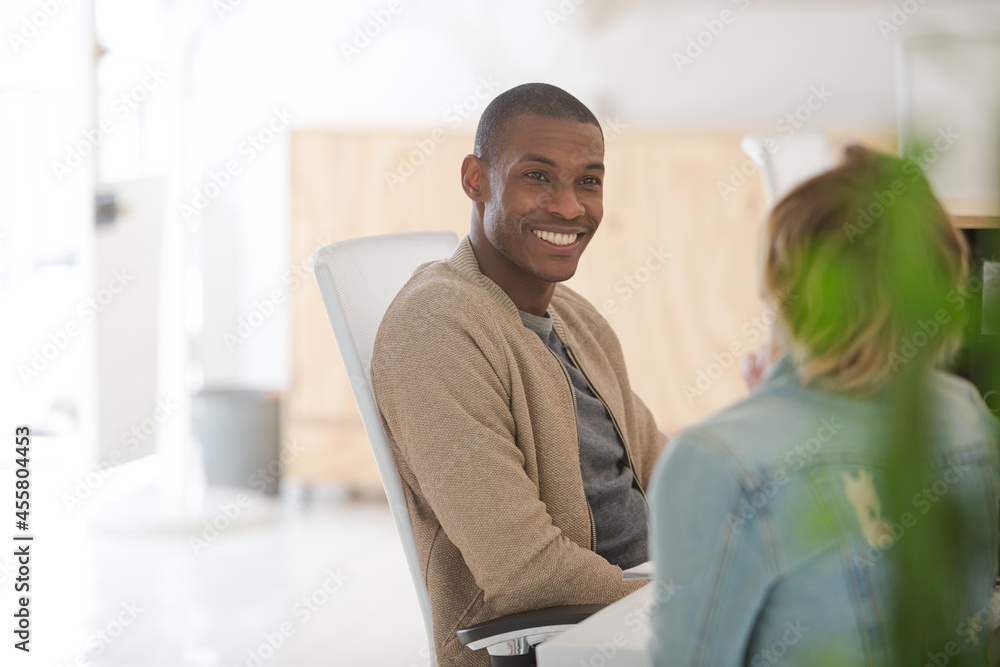 Obraz premium Man and woman sitting in office,smiling and talking