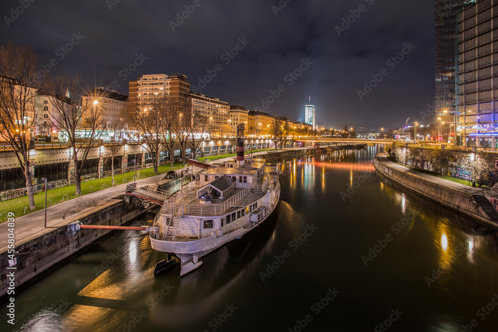 Long exposure night image of the canalized Danube river passing through the center of Vienna with a pleasure boat with fixed mooring