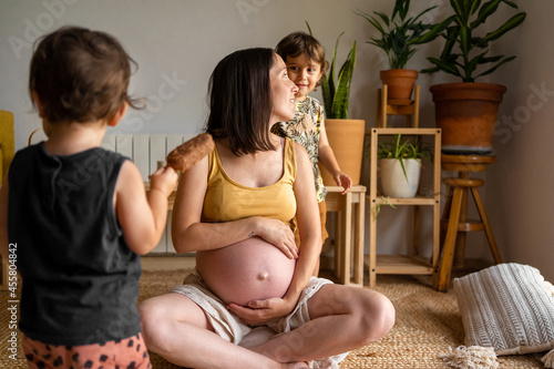 Gravid mum enjoying with her children at home