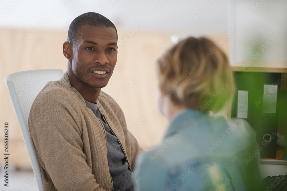 Fototapeta premium Man and woman sitting in office,smiling and talking