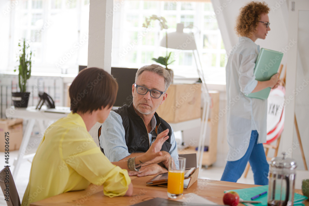 Man and woman sitting in office,smiling and talking Man and woman sitting in office,smiling and talking