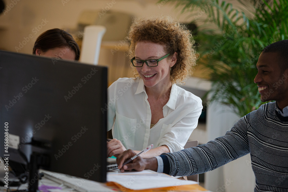 Fototapeta premium Office workers talking over computer at desk