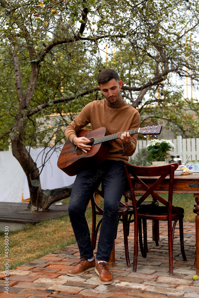 Obraz premium young man sits at the table and plays the guitar