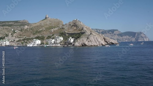 View of Balaklava bay with yachts from the Genoese fortress Chembalo in Sevastopol city. View from the marble beach to the exit from the bay to the open sea. In the background, Cape Aya Nature Reserve