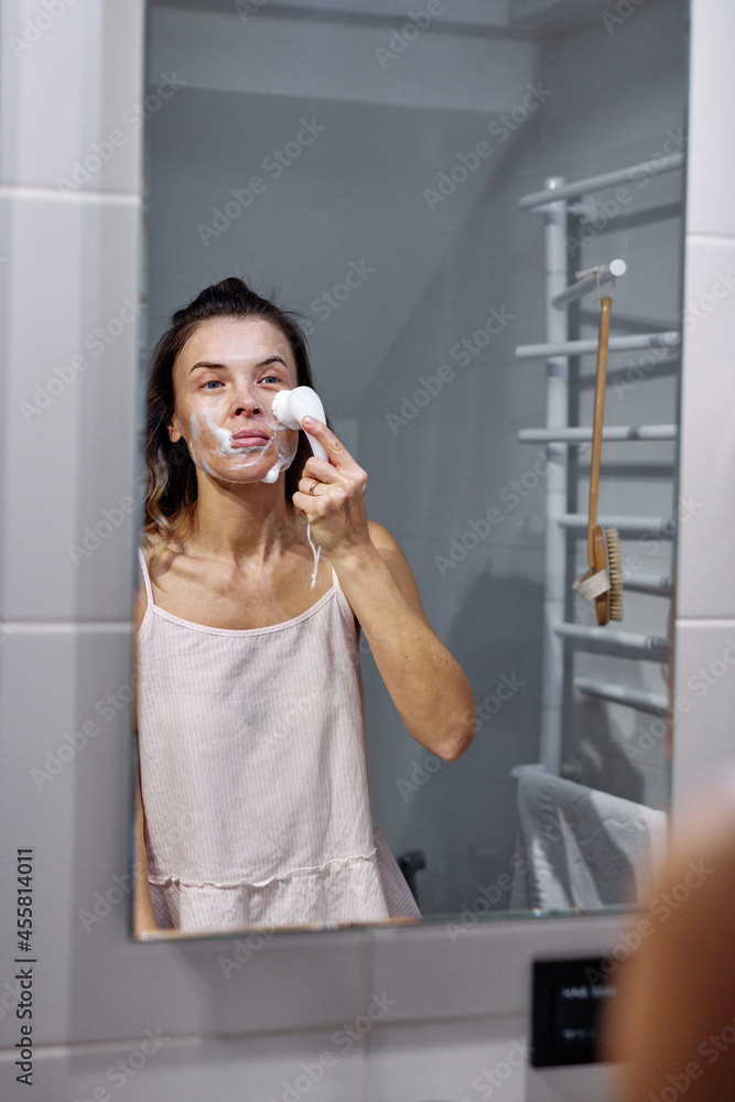 Pretty girl cleaning face in morning in bathroom Pretty girl cleaning face in morning in bathroom