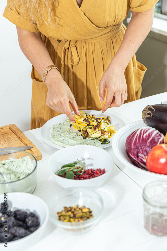 Young woman plating salad on dining table Young woman plating salad on dining table