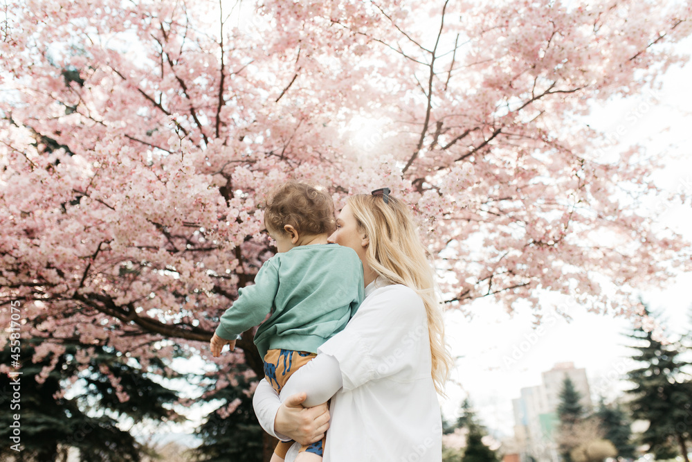 Mother holding a child under blossoming tree. Mother holding a child under blossoming tree.