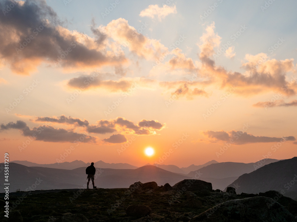 Silhouette of man walking in sunset in the Rocky Mountains.