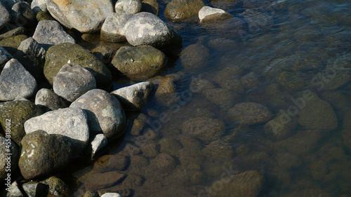 The stones and pebbles on the river bank, some are submerged in water