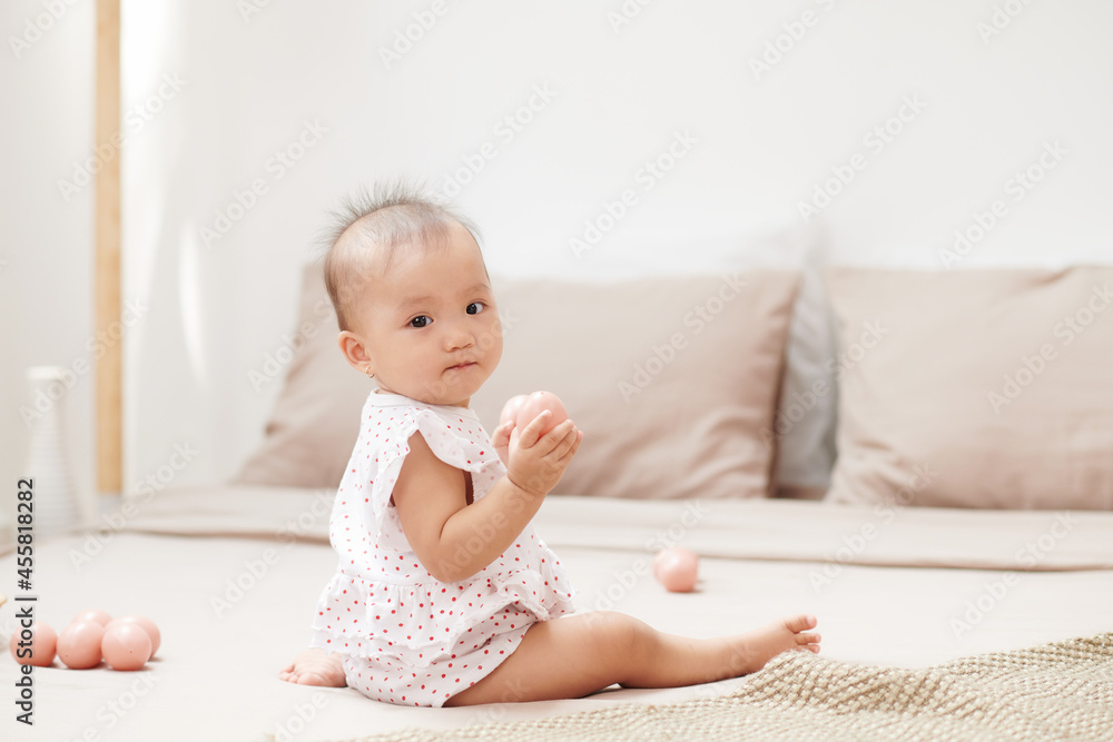 infant baby sitting on the bed with eggs toy infant baby sitting on the bed with eggs toy