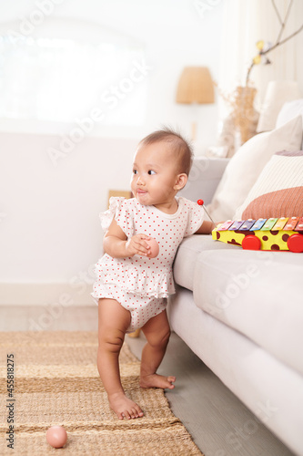 Cute active asian little baby girl is standing on the floor and trying begin to walk for first step herself