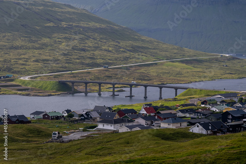Beautiful view of a small village  in the Faroe Islands, and its amazing bridge with its :churchs, grass roofs and colorful Houses in front of the ocean 