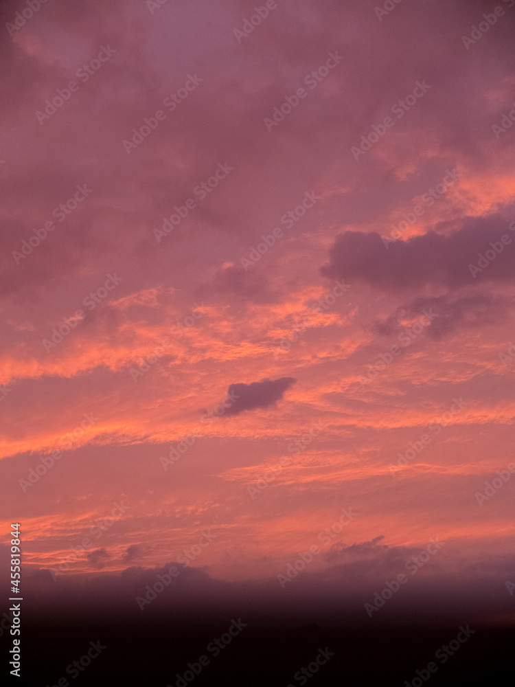 A cloudy sky during sunset with a blurred window frame.