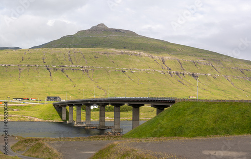Beautiful view of a small village  in the Faroe Islands, and its amazing bridge with its :churchs, grass roofs and colorful Houses in front of the ocean 