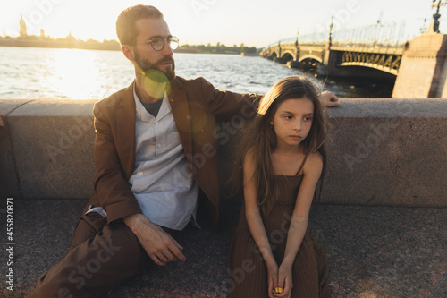 Man and confused child on the river bank photo