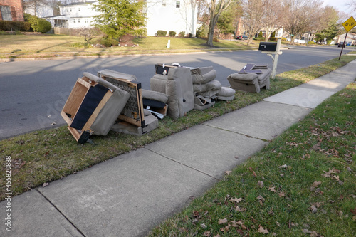 Old disassembled chairs and cushions lined up by the curb waiting to be disposed of by the garbage men on trash day photo