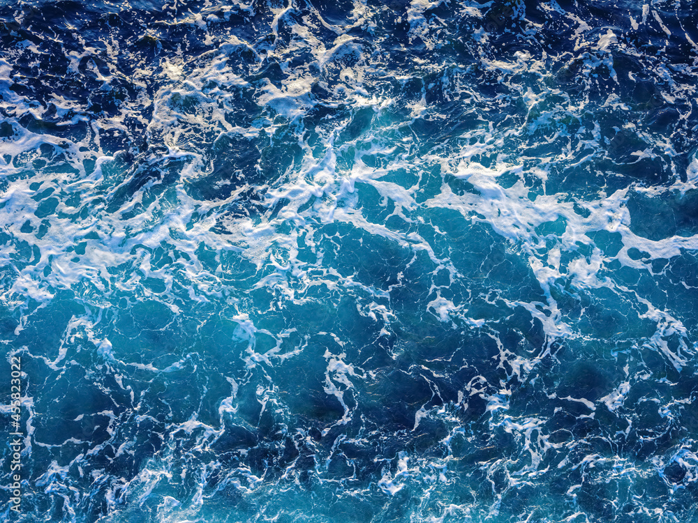 Rough deep turquoise and blue Pacific ocean with white foam texture background